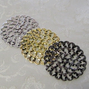 May include: Three decorative metal filigree circles in silver, gold, and black. Each circle has a delicate, intricate design of small hearts.