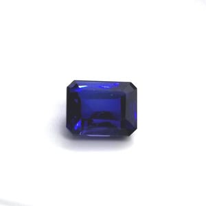 Puede incluir: Una gema rectangular de color azul oscuro con un corte facetado. La gema tiene un color rico y saturado y una superficie pulida, que refleja la luz. La forma es un corte esmeralda, con una disposición simétrica de facetas.