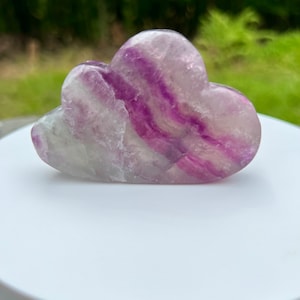 May include: A purple and white fluorite crystal carved into a cloud shape.