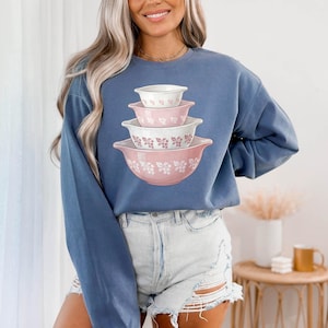 May include: A white ceramic mug with a black handle and the text "But First, Coffee" in a bold, black font. The mug is set against a neutral background, highlighting its simple design.