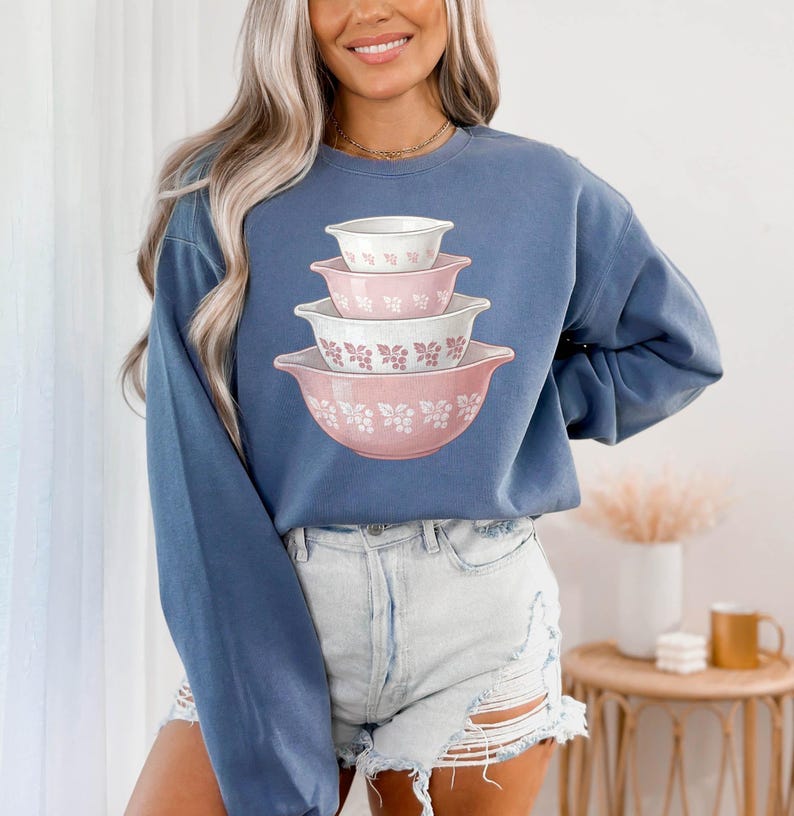 May include: A white ceramic mug with a black handle and the text "But First, Coffee" in a bold, black font. The mug is set against a neutral background, highlighting its simple design.