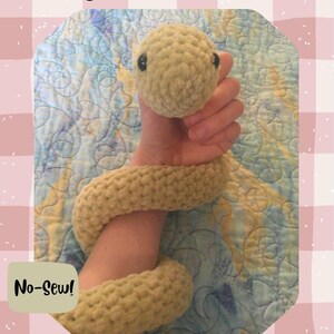 May include: A crocheted snake toy in a light tan color, with black button eyes. The snake is wrapped around an arm. Text on the image reads "Crochet Snake", "No-Sew!", and "CrochetbyAbrielle".