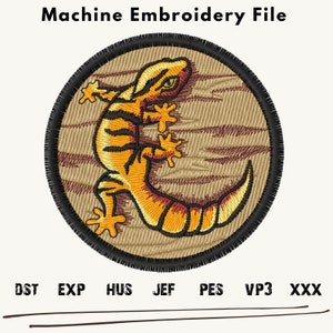 May include: A round machine embroidery file design featuring a yellow and orange gecko on a brown woodgrain background. The design is surrounded by a black outline and a frayed edge.