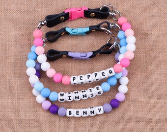 May include: Three colorful beaded dog collars with the names "Pepper", "Winnie", and "Benny" spelled out in white beads.