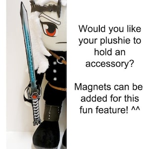 May include: A plush toy with white hair and a black outfit holding a blue and silver sword. The toy has red eyes and a crown. The text "Would you like your plushie to hold an accessory? Magnets can be added for this fun feature! ^^" is visible in the image.