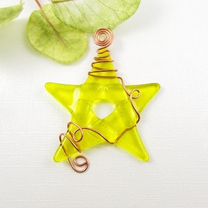 May include: A yellow glass star ornament with copper wire wrapped around it. The wire is twisted into a spiral at the top of the star.