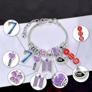 May include: A silver-toned charm bracelet featuring various purple, blue, and red charms, including a number 7, a butterfly, a music note, a logo with the text ARMY, and a logo with the text OT7, accented with purple crystals and silver beads.