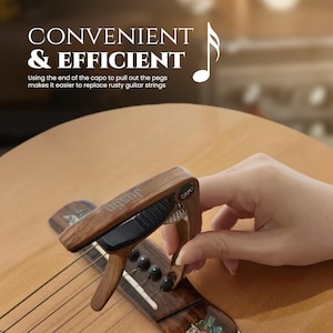 May include: A wooden capo with a black spring and a black lever. The capo is attached to a guitar fretboard. The text "uishe CAPO" is printed on the capo.