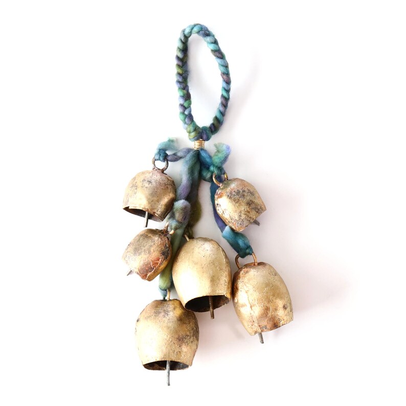 May include: A set of six gold-colored bells hanging from a blue and green braided rope. The bells are tied together with a blue and green fabric ribbon.