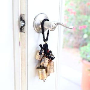 May include: A door handle with a black cord and a cluster of small gold bells hanging from it.