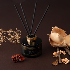 May include: Black glass diffuser bottle with gold accents and black diffuser sticks. The bottle has a label that reads "Loris Niche Oud & Ylang Ylang Pure Diffuser".