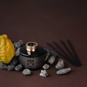 May include: Black glass diffuser bottle with a gold lid and black diffuser sticks. The bottle has a label that reads "Loris Niche Bergamot & Powdery Rose Diffuser".