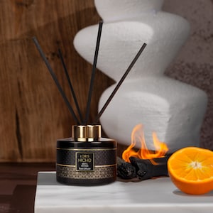 May include: A black glass bottle with a gold lid and black reeds. The bottle has a label that says "Loris Niche Mint & Orange Reed Diffuser".