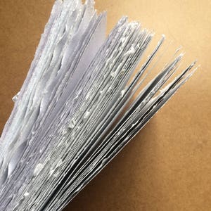 May include: A stack of handmade paper with rough edges, showing the individual sheets and the texture of the paper.