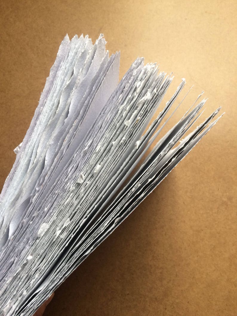 May include: A stack of handmade paper with rough edges, showing the individual sheets and the texture of the paper.