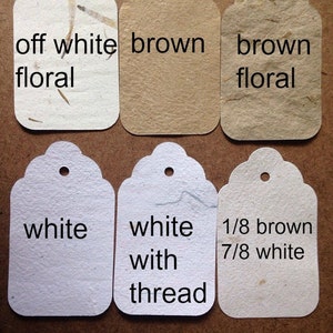 May include: Six different paper gift tags with scalloped edges. The tags are in various shades of brown and white, including off-white floral, brown, brown floral, white, white with thread, and 1/8 brown 7/8 white.