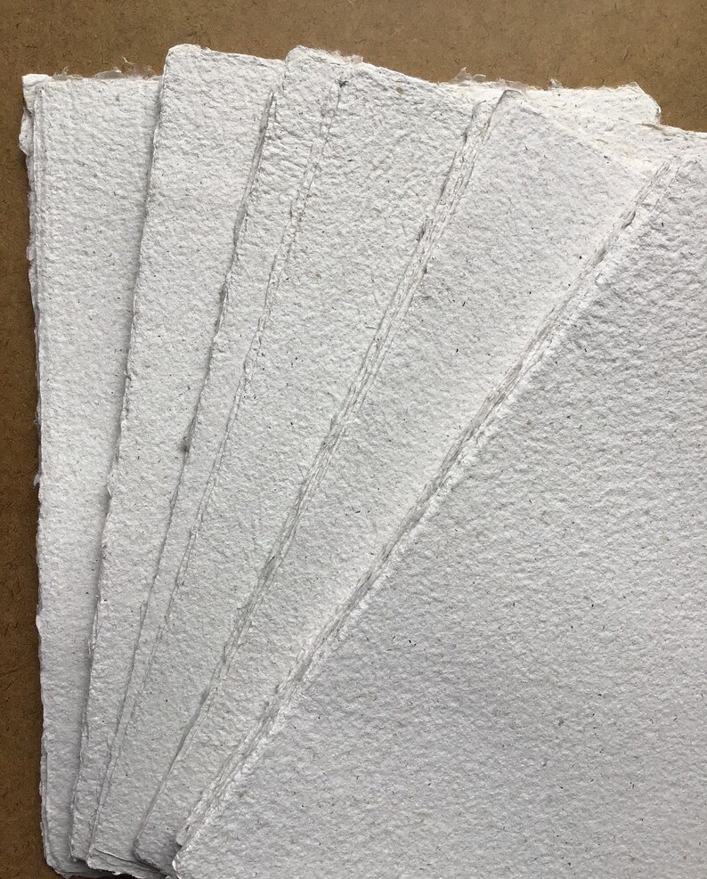 May include: A stack of white handmade paper sheets with a rough, textured surface.