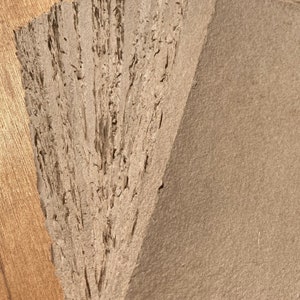 Może przedstawiać: Stos brązowych arkuszy ręcznie robionego papieru o szorstkiej, fakturowanej powierzchni.