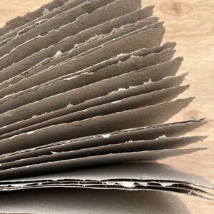 Puede incluir: Una pila de hojas de papel marr&oacute;n con bordes &aacute;speros, que muestran las capas del papel.