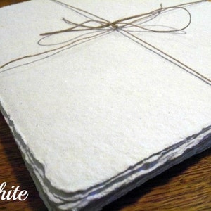 May include: A stack of white handmade paper sheets tied together with twine. The paper has a rough, textured surface.