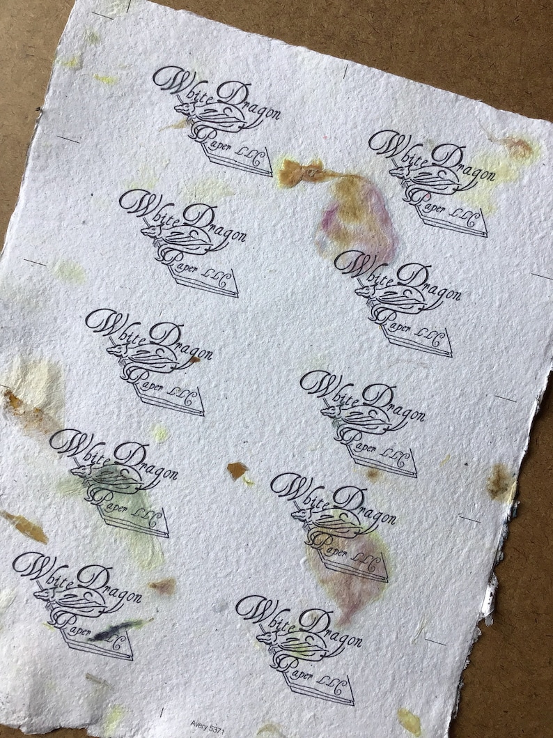 Może przedstawiać: Arkusz białego papieru z wieloma stemplami czarno-białego logo z napisem "White Dragon Paper LLC". Papier ma brązowe, ż&oacute;łte i fioletowe plamy.