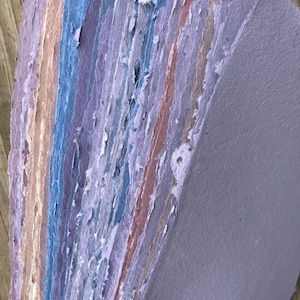 May include: A stack of handmade paper sheets in various shades of purple, blue, and pink. The paper has a textured, handmade look and feel.