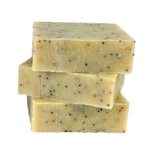 May include: Three bars of handmade soap with a light green color and black poppy seeds. The soap is stacked on top of each other.