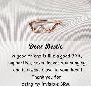 May include: A rose gold ring with a wavy design and two small spheres. The ring is on a white and gray striped background. The text "Dear Bestie" is above a quote about friendship.