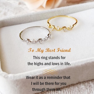 May include: Two delicate rings, one silver and one gold, each adorned with small, sparkling stones. The rings are displayed on a white surface, with text that reads "To My Best Friend" and a message about friendship.