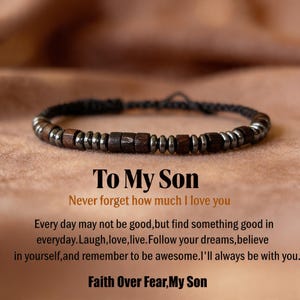 May include: A dark brown and silver beaded bracelet with the text "To My Son" and a message of love and encouragement. The bracelet features wooden and metallic beads strung on a black cord. The text is in a white and orange font.