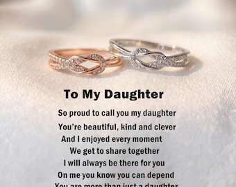 Puede incluir: Dos anillos con un diseño de nudo central incrustado con pequeñas piedras claras. Un anillo es de tono oro rosa y el otro de tono plateado. Debajo de los anillos hay un texto que dice: To My Daughter, So proud to call you my daughter, You’re beautiful, kind and clever, And I enjoyed every moment, We get to share together, I will always be there for you, On me you know you can depend, You are more than just a daughter, You are my BEST FRIEND.