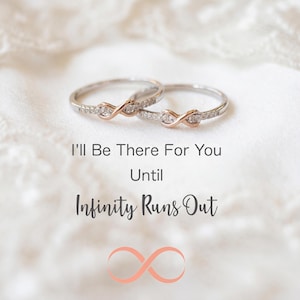 May include: Two silver rings with rose gold infinity symbols and small clear stones. The rings are on a white lace surface. Text reads "I'll Be There For You Until Infinity Runs Out."