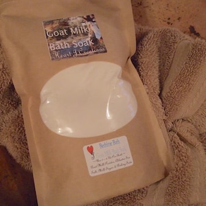 May include: A brown paper bag with a white label that says "Goat Milk Bath Soak Heart I Creations". The bag contains a white powder and a smaller label that says "Bedtime Bath Goat Milk Bath Soak - How to - 1/2 Cup Per Bath - Goat Milk Powder, Atlantic Sea Salt, Milk Sugar & Baking Soda".