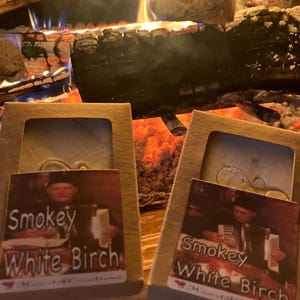 Puede incluir: Dos cajas de cart&oacute;n marr&oacute;n con etiquetas blancas. Las etiquetas tienen una imagen de una persona sosteniendo una barra de jab&oacute;n. El texto en las etiquetas dice "Smokey White Birch".