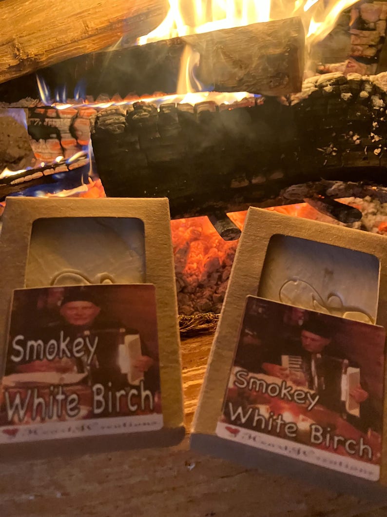 Puede incluir: Dos cajas de cart&oacute;n marr&oacute;n con etiquetas blancas. Las etiquetas tienen una imagen de una persona sosteniendo una barra de jab&oacute;n. El texto en las etiquetas dice "Smokey White Birch".