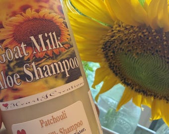 May include: A cylindrical bottle of Patchouli Goat Milk Shampoo with a label featuring a sunflower image and text including Goat Milk Aloe Shampoo, Hearty Creations, and a list of ingredients like Aloe Vera Juice and oils, totaling 8 oz.