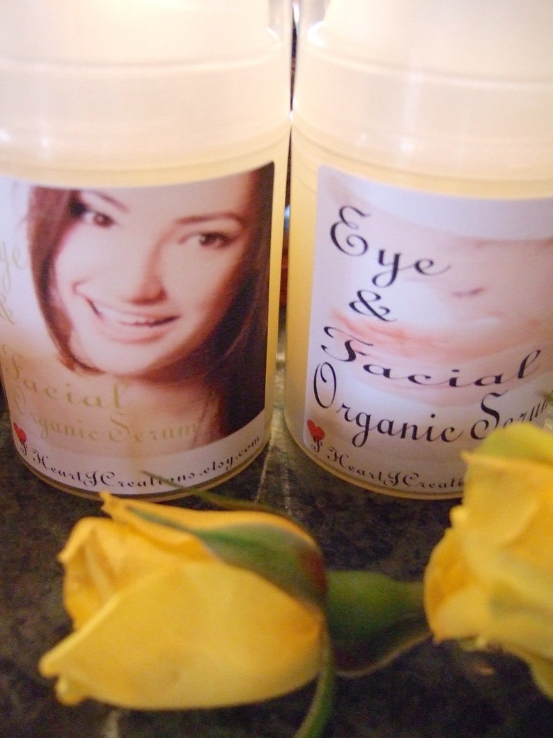 Puede incluir: Dos botellas de vidrio transparente con etiquetas blancas. Las etiquetas tienen texto negro que dice "Eye & Facial Organic Serum" y "Facial Organic Serum". Las botellas est&aacute;n sobre una superficie marr&oacute;n con rosas amarillas en primer plano.