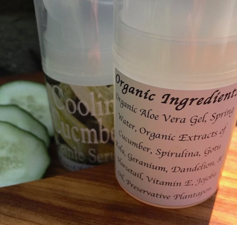May include: Two clear plastic bottles with white labels. The label on the front bottle reads "Cooling Cucumber Facial Serum". The label on the back bottle reads "Organic Ingredients: Organic Aloe Vera Gel, Spring Water, Organic Extracts of Cucumber, Spirulina, Gotu Kola, Geranium, Dandelion, & Horsetail, Vitamin E, Jojoba Oil, Preservative Plantapon".