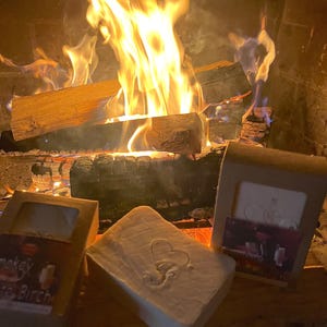 Puede incluir: Tres barras de jab&oacute;n artesanal delante de una chimenea. Las barras de jab&oacute;n est&aacute;n envueltas en papel marr&oacute;n con texto blanco. El texto en las barras de jab&oacute;n dice "Smokey Birch", "Lavender & Eucalyptus" y "Cranberry & Orange".