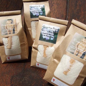 May include: Four brown paper bags filled with white laundry soap. Each bag has a label with the text "Laundry Soap" and instructions for use. The text on the labels reads: "Use 1-2 Tbsp per load. Ground Coco Butter Soap, Soda Ash, Borax, Baking Soda. Heart Creations Etsy.com."