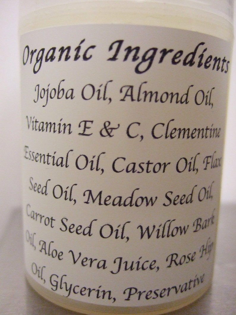 Puede incluir: Una etiqueta blanca con texto negro que enumera los ingredientes org&aacute;nicos de un producto. Los ingredientes incluyen aceite de jojoba, aceite de almendras, vitamina E y C, aceite esencial de clementina, aceite de ricino, aceite de linaza, aceite de semilla de prado, aceite de semilla de zanahoria, aceite de corteza de sauce, jugo de aloe vera, aceite de rosa mosqueta, glicerina y conservante.