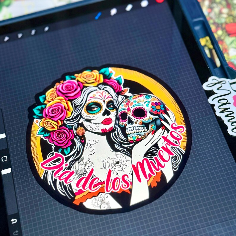 May include: A circular sticker design featuring a woman with sugar skull makeup, wearing a crown of yellow and pink roses, holding a decorated skull. The text "Dia de los Muertos" is written in pink script across the bottom of the illustration.