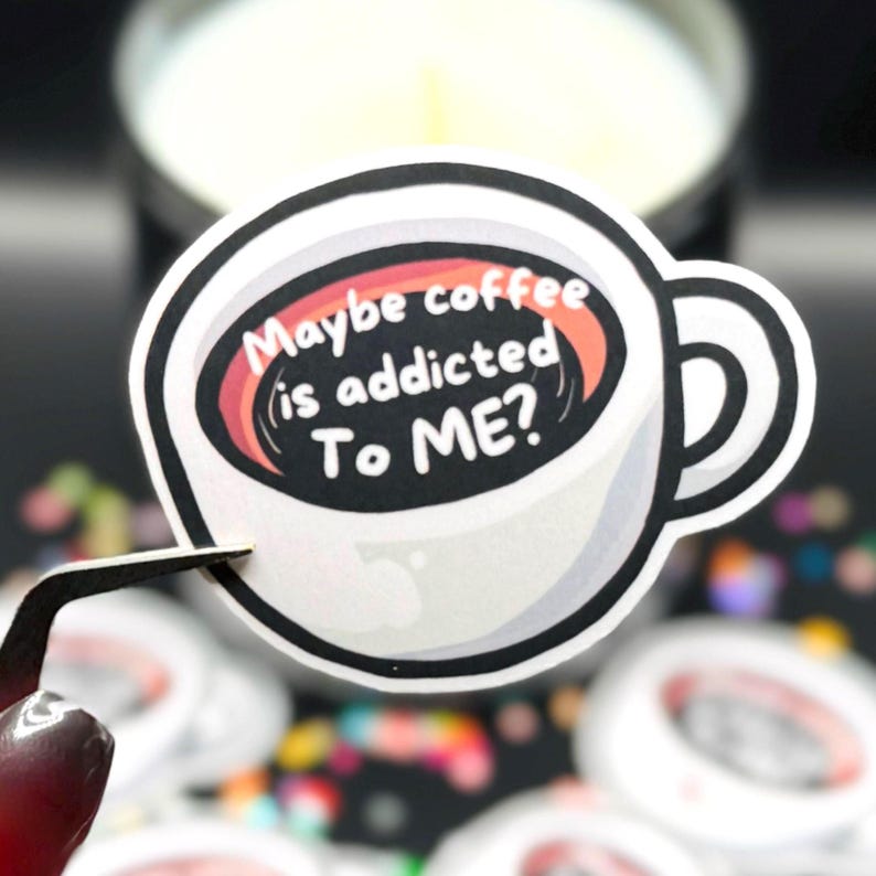 May include: A die-cut sticker shaped like a coffee mug with a white exterior and a black interior. The text "Maybe coffee is addicted To ME?" is printed in white letters inside the mug. The design features a thick black outline and a handle.