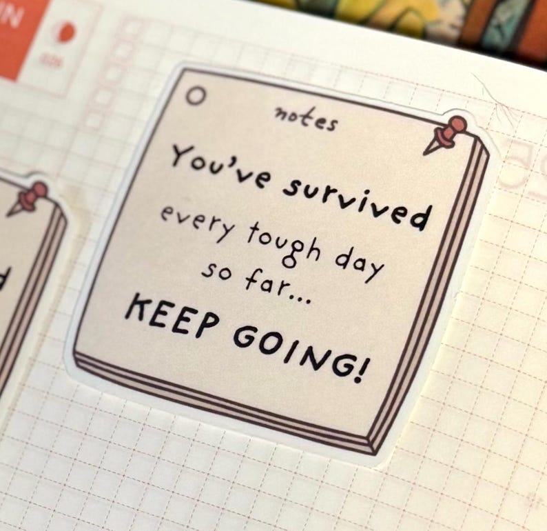 May include: A square beige sticker shaped like a notepad page with a brown border and a small red pushpin graphic in the corner. The text reads notes, You've survived every tough day so far... KEEP GOING! in a dark brown handwritten font style.