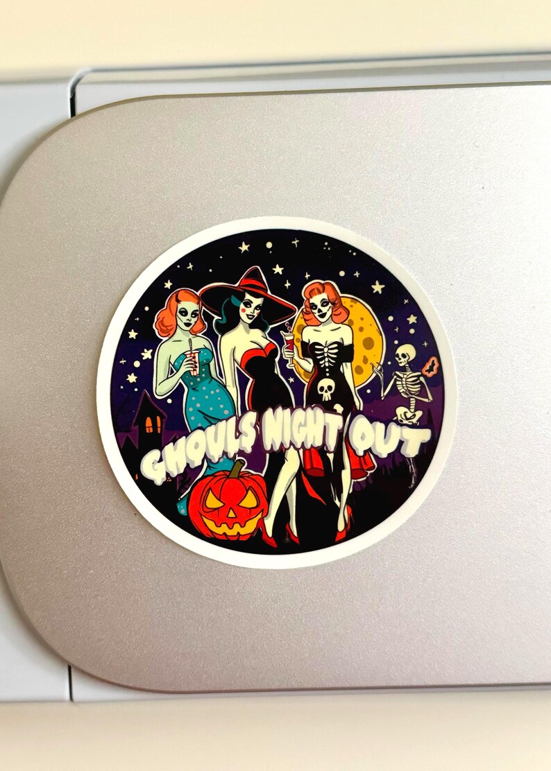 May include: A circular sticker featuring three stylized figures in Halloween attire, a skeleton, and a jack-o'-lantern against a starry night sky. The text GHOULS NIGHT OUT is printed in white, bold, bubbly letters across the center of the design.