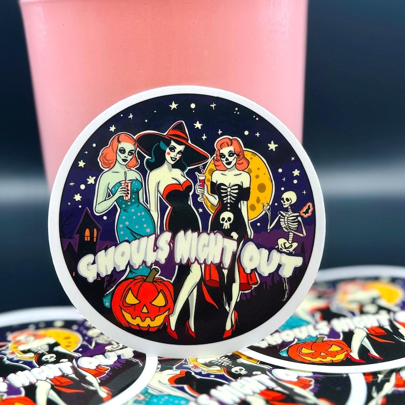 May include: A circular sticker featuring three figures in costumes, a jack-o'-lantern, and a skeleton against a dark starry night sky. The text GHOULS NIGHT OUT is printed in white across the center. The design includes a house silhouette.