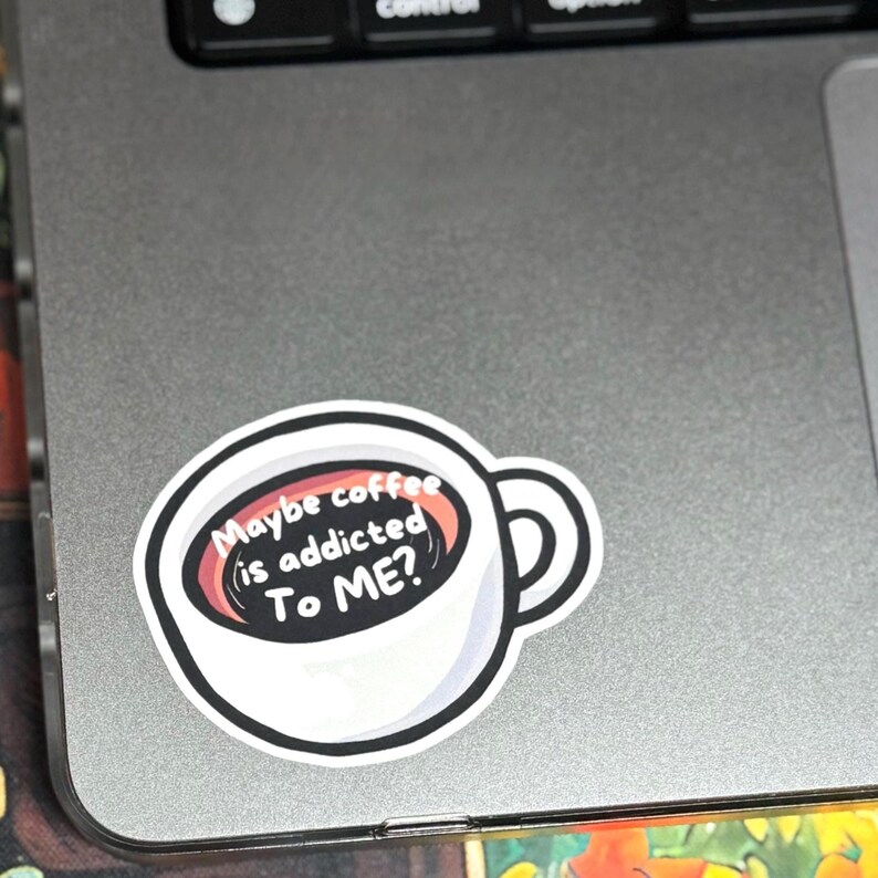 May include: A white coffee mug sticker with a black interior and a thick black outline. The liquid inside the mug features the white text "Maybe coffee is addicted To ME?" written in a bold, sans-serif font against the dark background.