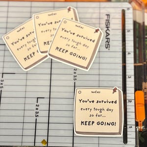 May include: Four square stickers shaped like sticky notes with a cream background and black text that reads: notes, You've survived every tough day so far... KEEP GOING! Each sticker features a small red pushpin graphic in the top right corner.