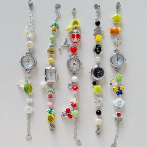 May include: Five colorful charm bracelets with watches attached. Each bracelet features a different theme with charms like flowers, butterflies, pineapples, and stars.