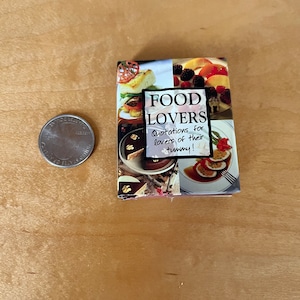 Könnte beinhalten: Ein kleines, rotes Buch mit dem Titel "Food Lovers" und dem Text "quotations for lovers of their tummy!" Das Cover zeigt eine Collage von Bildern mit Essen.